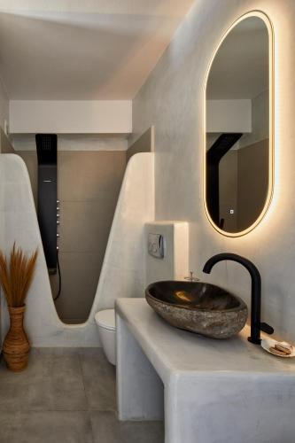 a bathroom with a stone sink and a mirror at Bluewhite Suites & Villa Santorini in Pirgos