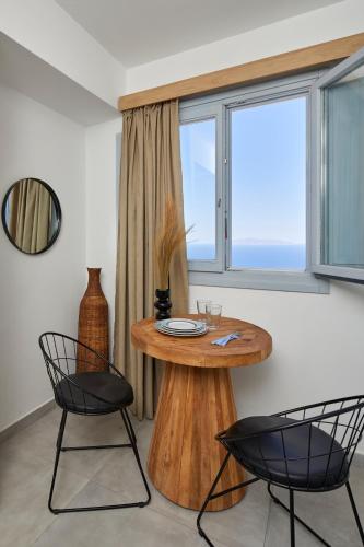 a table and two chairs in a room with a window at Bluewhite Suites & Villa Santorini in Pirgos