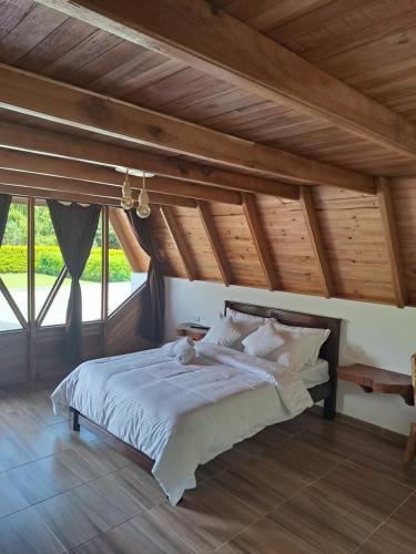 sypialnia z dużym łóżkiem i drewnianym sufitem w obiekcie Cabañas Amalú w mieście San Agustín