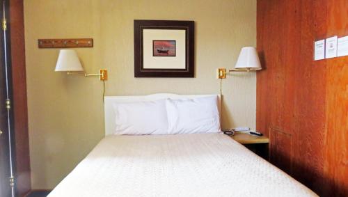 a bed in a hotel room with two lamps on the wall at Indianhead Ironwood Hotel in Ironwood