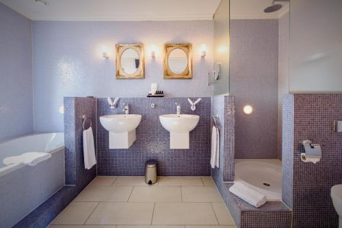 een badkamer met 2 wastafels, 2 spiegels en een bad bij Villa Beukenhof in Oegstgeest