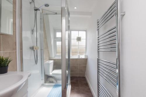 uma casa de banho com um chuveiro, um WC e um lavatório. em Pass the Keys Comfy Apartment by Oval Station em Londres