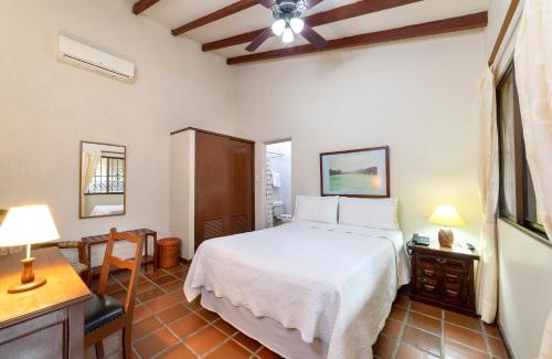 a bedroom with a white bed and a table and a desk at Hotel Stein Colonial in Cali