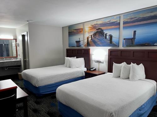 a hotel room with two beds and a painting on the wall at Days Inn by Wyndham Greenville in Greenville