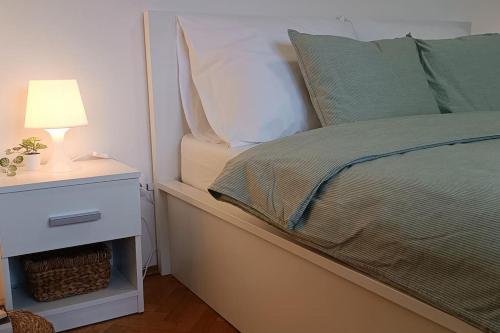 Plitvice Green Apartment في بليتفيتْشكا ييزيرا: سرير مع موقف ليلي مع مصباح عليه
