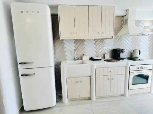 La cuisine est équipée d'un réfrigérateur blanc et d'un évier. dans l'établissement Gerani Deluxe Houses, à Astypalée