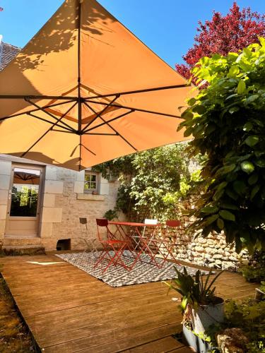 a large orange umbrella sitting on a wooden deck at Le Lavoir aux Roses by Gîtes Sud Touraine in Chédigny