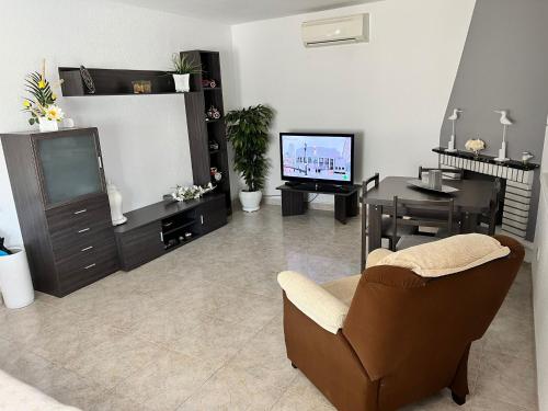 sala de estar con TV, silla y mesa en Chalet con piscina privada en Vinarós