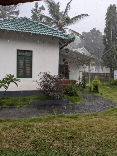 a house in the rain in front of a yard at Multiple Stories, Wayanad in Wayanad