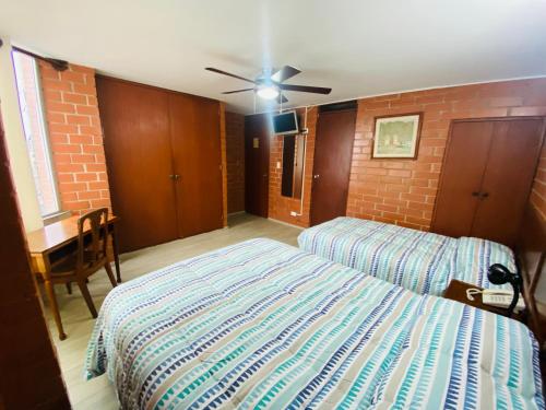 a bedroom with two beds and a ceiling fan at Hotel Esperanza in Lima