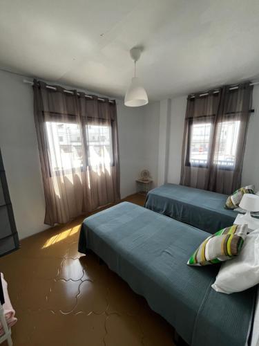 1 dormitorio con 2 camas y 2 ventanas en CASA DOMINGO 2, en La Santa