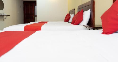 two beds in a hotel room with red and white pillows at Hotel Esperanza, Oaxaca Centro in Oaxaca City