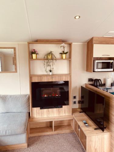 a living room with a tv and a fireplace at 8 Bed Sun Decked Caravan Unlimited High speed Wifi and fun at Seawick Holiday Park in Clacton-on-Sea