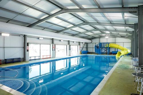 a large swimming pool with a slide in a building at 8 Bed Sun Decked Caravan Unlimited High speed Wifi and fun at Seawick Holiday Park in Clacton-on-Sea