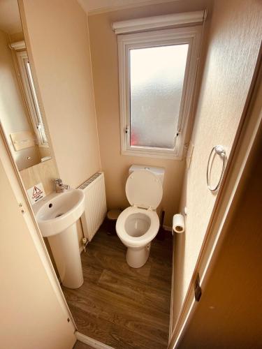 a small bathroom with a toilet and a sink at 8 Bed Sun Decked Caravan Unlimited High speed Wifi and fun at Seawick Holiday Park in Clacton-on-Sea