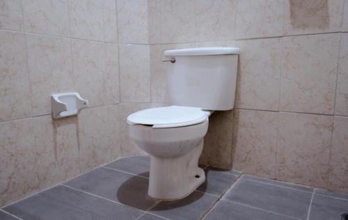 a white toilet in a bathroom with a toilet paper dispenser at Hotel Esperanza, Oaxaca Centro in Oaxaca City