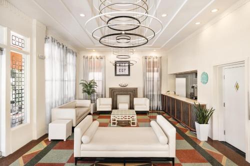 una sala de estar con muebles blancos y una lámpara de araña. en Waldorf Towers South Beach en Miami Beach