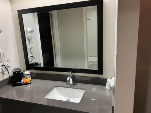 La salle de bains est pourvue d'un lavabo et d'un grand miroir. dans l'établissement GARDEN INN & Suites, à Hebbronville