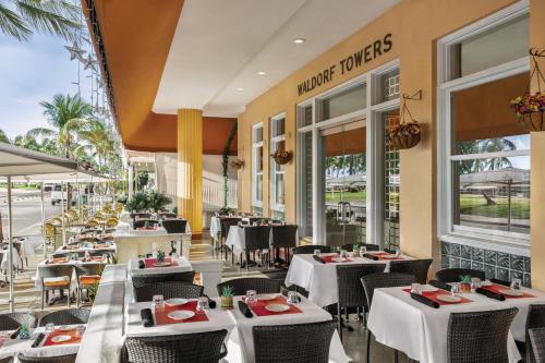 un restaurante con mesas y sillas blancas y ventanas en Waldorf Towers South Beach en Miami Beach