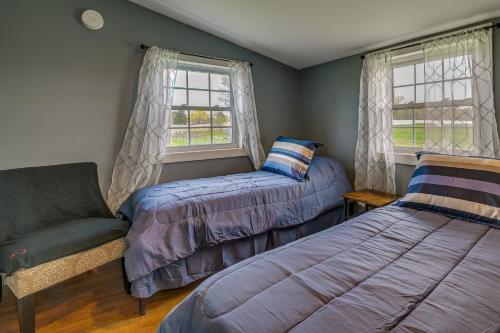 1 dormitorio con 2 camas, silla y ventanas en Upstate New York Vacation Rental Near Cooperstown!, en Cherry Valley