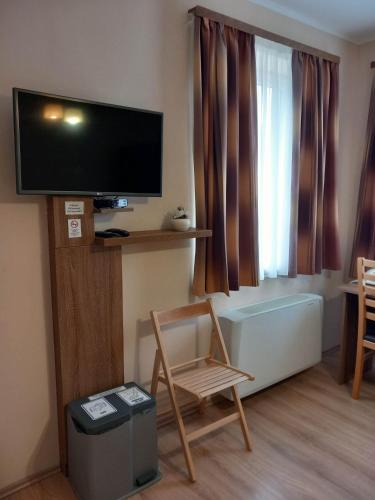 a living room with a flat screen tv and a chair at Kata Panzió in Oroszlány