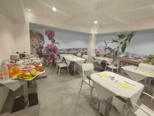 un comedor con mesas blancas y sillas blancas en Profumi di Primavera Luxury Rooms en Matera