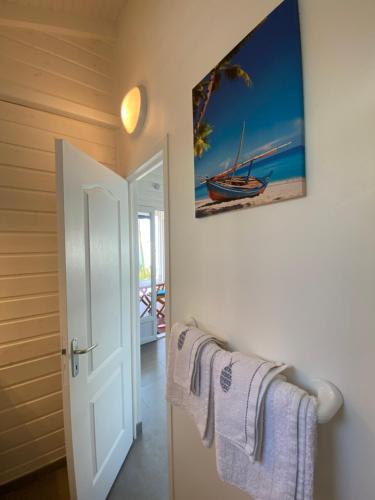 a bathroom with white towels and a picture of a boat at Bungalow Palbéa supérieur avec SPA et vue mer in Schœlcher