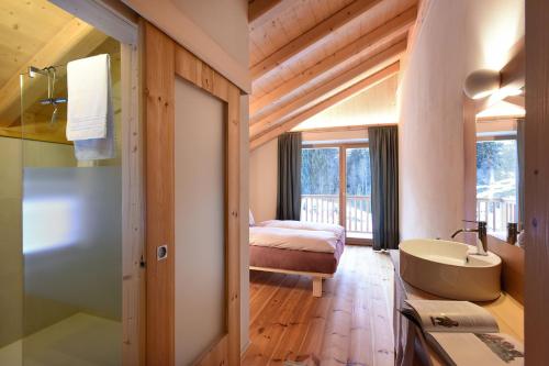 a bathroom with a sink and a bed and a tub at B&B Mas de Lagorae in Tesero