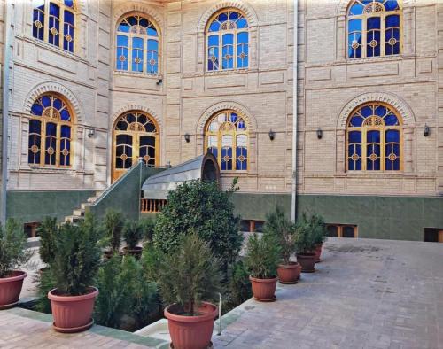 Um edifício com um monte de vasos de árvores à frente. em Hotel KAMILA Prime em Samarkand