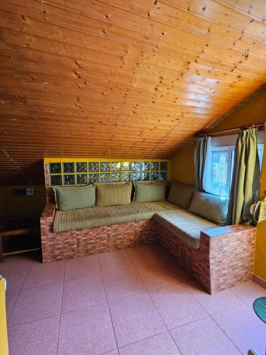 a couch in a room with a wooden ceiling at Finca rural Labriega del hueznar in Cazalla de la Sierra