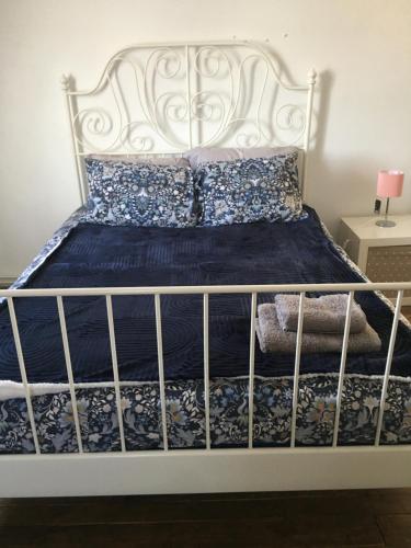 Bett mit einem weißen Bettrahmen und einer blauen Bettdecke in der Unterkunft Moore Crescent in Barking