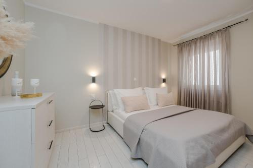 a white bedroom with a white bed and a window at Villa Karla in Zadar