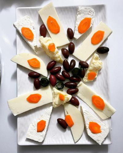 a plate of appetizers with cheese and vegetables at GRAND JNK Boutique Hotel in Kukës