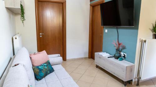 a living room with a white couch and a flat screen tv at Magda's garden home. in Galatás