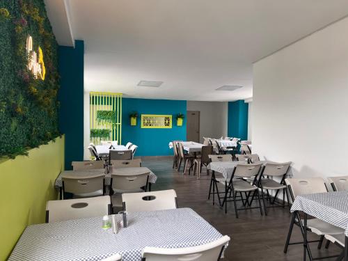 Hotel Rosales Gold في بيريرا: مطعم بطاولات بيضاء وكراسي وجدران زرقاء