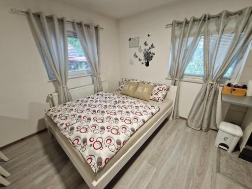 ein Schlafzimmer mit einem Bett und zwei Fenstern in der Unterkunft Guesthouse Ella in Slunj