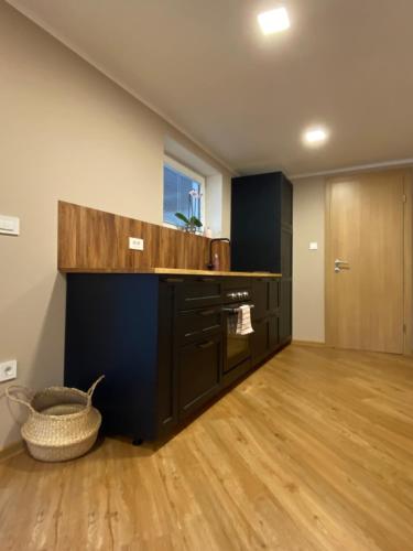 a kitchen with black cabinets and a wooden floor at Apartma LIMA in Mozirje