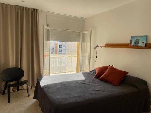 een slaapkamer met een bed, een stoel en een raam bij Apartamento en Vilanova i la Geltrú in Vilanova i la Geltrú