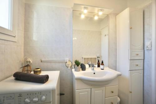 une salle de bain blanche avec un lavabo et un miroir dans l'établissement La Baie, à Concarneau