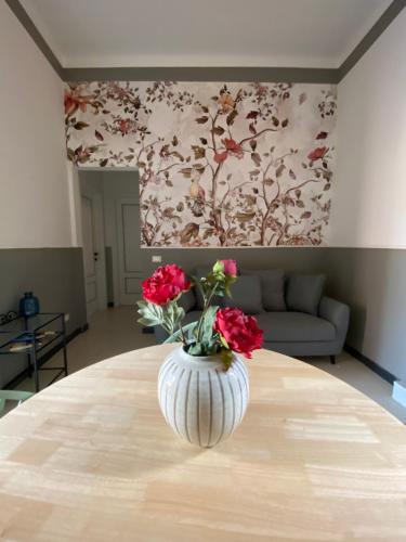 un vase avec des fleurs rouges assis sur une table dans l'établissement Blom apartments, à Pise