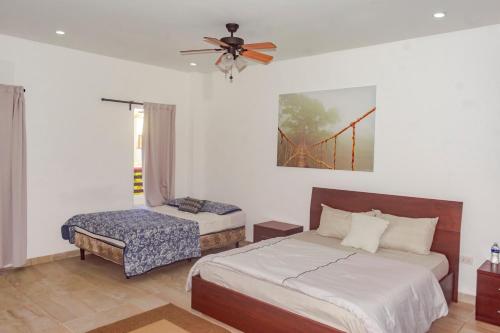 a bedroom with two beds and a fan and a chair at Las Palmas Beach Hotel in Dixon Cove