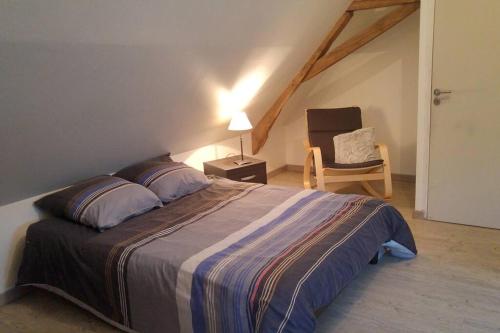 een slaapkamer met een groot bed en een stoel bij 24 Heures du Mans - GITE du Moulin du Breil in Écommoy