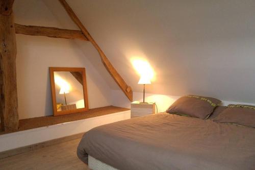 een slaapkamer met een groot bed en een spiegel bij 24 Heures du Mans - GITE du Moulin du Breil in Écommoy