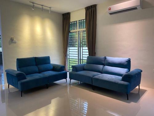 una sala de estar con 2 sofás azules y una ventana en GEYI HOMESTAY en Jerantut