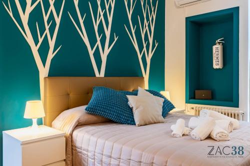 a bedroom with a bed with blue walls and a tree mural at ZAC 38 in Polignano a Mare