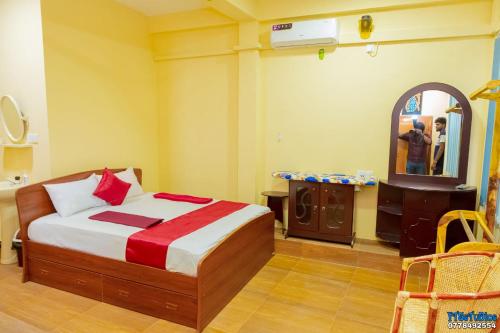 a bedroom with a bed and a mirror in it at UK Inn Guest House in Jaffna