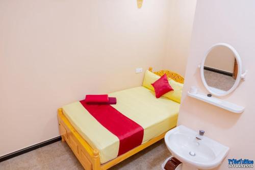 niewielka sypialnia z łóżkiem z lustrem i umywalką w obiekcie UK Inn Guest House w mieście Dżafna