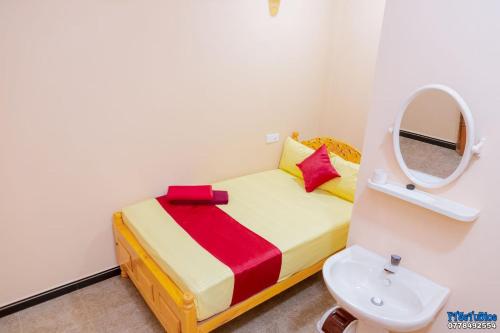 a small bedroom with a bed with a mirror and a sink at UK Inn Guest House in Jaffna