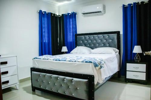 Schlafzimmer mit einem großen Bett und blauen Vorhängen in der Unterkunft 3 BR apartment ciudad santiago de los caballeros in Santiago de los Caballeros