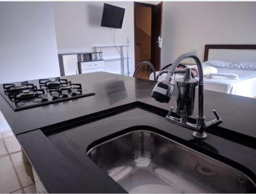 a kitchen with a sink and a black counter top at Vila Chale in Bauru